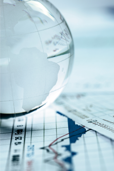 A transparent glass globe resting on printed financial stock market charts and graphs.