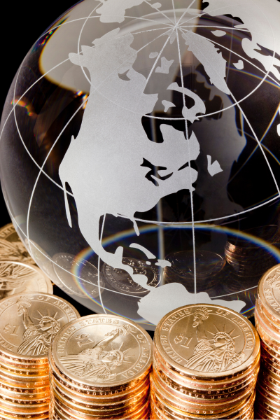 A glass globe showing the North American continent surrounded by stacks of US one-dollar coins.